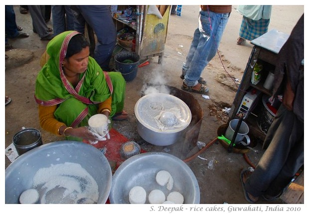 Woman cooking rice cakes on roadside, Guwahati, Assam, India